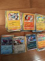 Stacks of sleeved and unsleeved Pokémon cards, fronts showing holo and rare cards