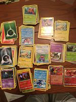 Stacks of assorted Pokémon cards including energy and holo reverse cards