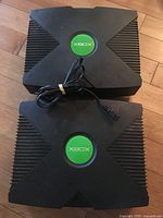 Two original Xbox consoles stacked with power cord