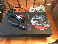 PlayStation 2 console with power and AV cables and Resident Evil 4 disc