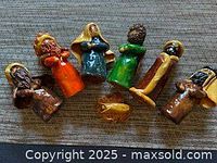 All seven ceramic nativity pieces laid flat showing size and colours