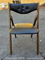 Front view of Willkie folding chair showing black vinyl seat and tufted backrest