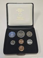 Open case showing all seven coins seated in black velvet insert and interior lid text