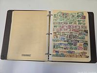 Open binder showing blank left page and right page filled with assorted vintage stamps