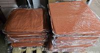 Stacked rust-orange cushions wrapped in plastic