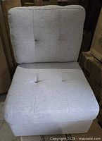 Front view of light grey upholstered armless sofa chair showing tufted seat and back