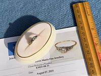 Ring displayed on oval case atop appraisal sheet with ruler for scale