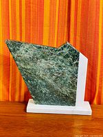 Full view of abstract green Heartenite sculpture with white stone side frame and base