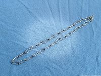 Full view of entire necklace laid flat on blue fabric