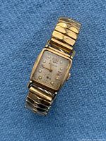 Front view showing dial with diamond and ruby chips, gold-tone case, expansion bracelet