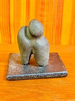 Front view of grey speckled abstract stone figure on rectangular base