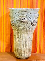 Full view of stoneware vase showing height, vertical ribbing and relief motifs
