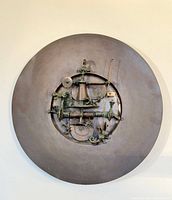 Full view of circular bronze wall sculpture mounted on wall
