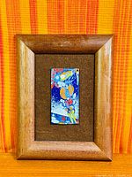 Full view of framed enamel artwork showing plaque, mat, and wood frame