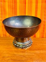 Side view of bronze pedestal bowl highlighting hammered texture and foot decoration
