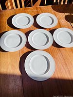 Six white Rosenthal plates arranged on wooden table