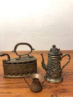 Group shot of brass coal iron, ornate coffee pot and copper jug