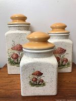 Front view of three ceramic mushroom canisters showing design and size comparison