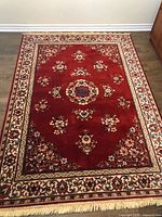 Full view of red floral area rug with fringe