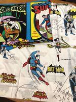 Close view of bed sheet and curtain showing multiple superhero graphics