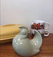 Overall lot view showing Tupperware server, bird figurine, two mugs