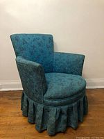 Front view of turquoise barrel armchair showing upholstery, seat cushion and pleated skirt