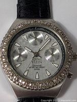 Close-up of watch face showing brand, bezel stones, subdials and dial pattern