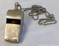 Front angled view of metal whistle with bead chain attached