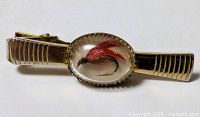 Full view of gold-tone tie clip with lure cabochon
