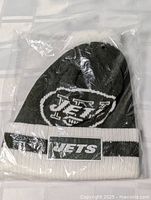 Sealed package showing full beanie front with logos