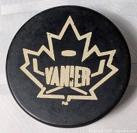 Top view showing beige maple leaf VANIER logo on black puck