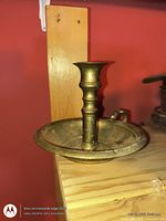 Side view of brass chamberstick on shelf