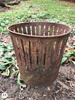 Full view of rusted iron slotted bin standing on ground