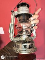 Front view of Beacon metal kerosene lantern with handle raised
