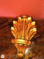 Front view of gold clam shell sconce laying on surface
