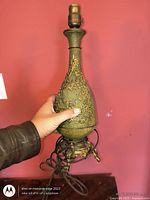 Lamp held upright showing body shape, relief pattern, cord and base