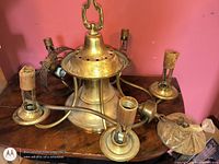 Full view of brass ceiling light fixture, showing central body, four socket arms, canopy, and chain