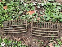 Pair of curved cast iron grates lying on ground