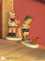 Front view of both Hummel figurines on shelf