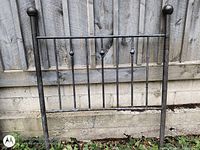 Front view of brass headboard against fence