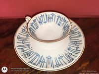 Top view of teacup on saucer showing blue line pattern and gold trim