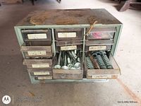 Front view of green metal organizer showing all drawers; two drawers open revealing carriage bolts and washers