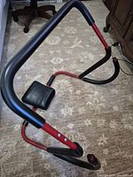 Front view of red and black ab roller showing full frame and headrest pad