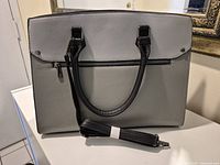 Front view of grey tote showing handles, zipper pocket and strap