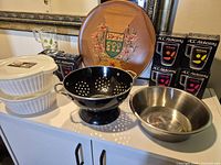 Group shot of all kitchen items including casseroles, mugs, colander, bowls, wooden platter
