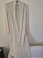 Full view of long cream cardigan hanging