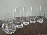 Front view of four footed crystal tumblers and cut crystal creamer