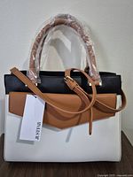 Front view showing colorblock design, handles wrapped, brand tag and strap