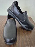 pair of black Dakota slip-on shoes on tabletop
