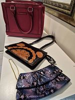 Overall view showing three handbags on surface